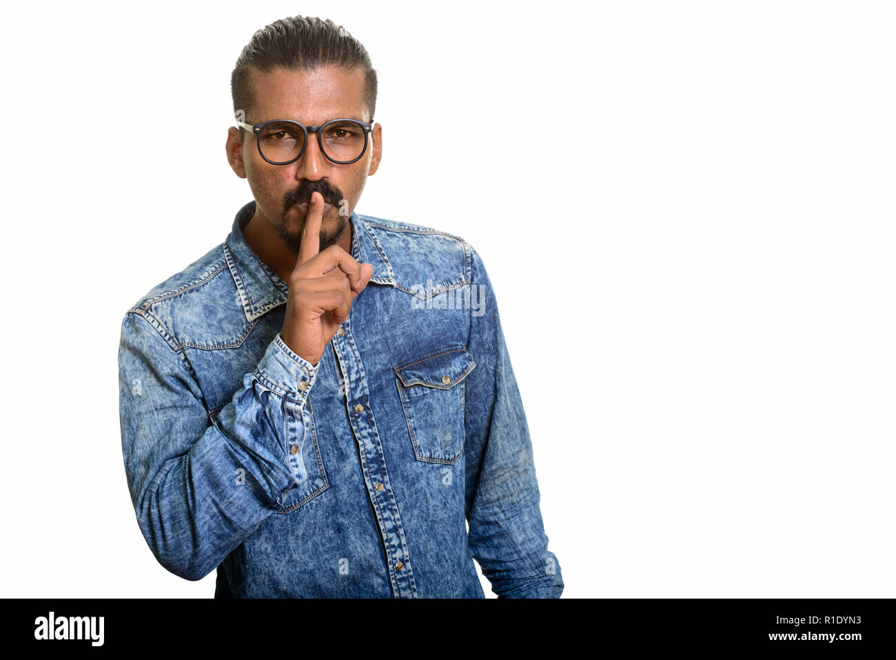 Young Indian man with finger on lips Stock Photo