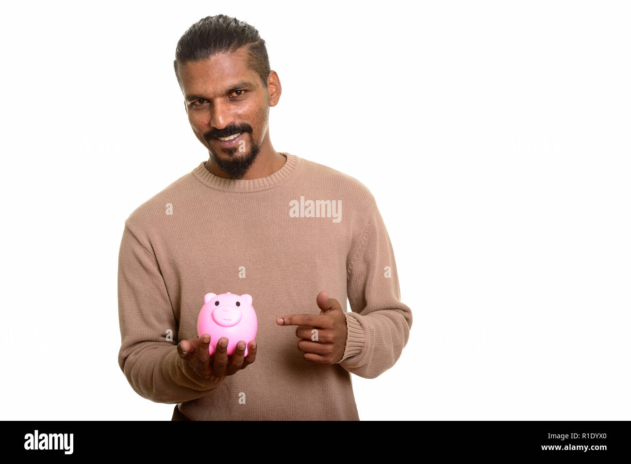 Young happy Indian man holding piggy bank and pointing finger Stock ...