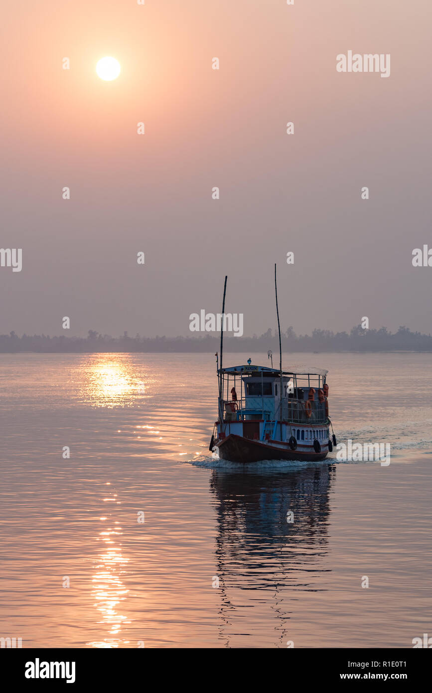 A passenger ferry boat is silhouetted against the setting sun in the Sundarbans, West Bengal, India. Stock Photo