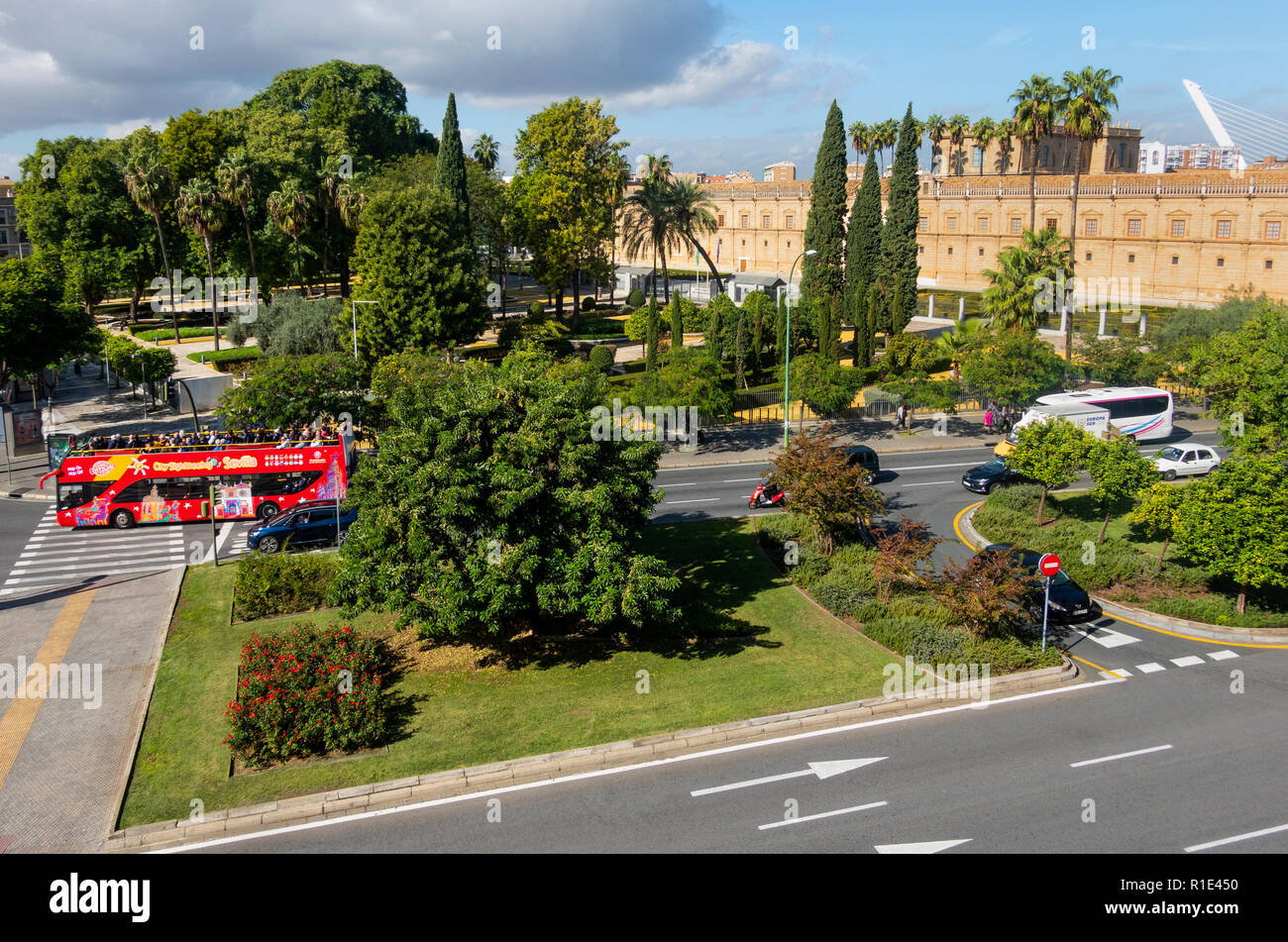 Bright red open top site-seeing bus passing a park in Seville, Spain Stock Photo