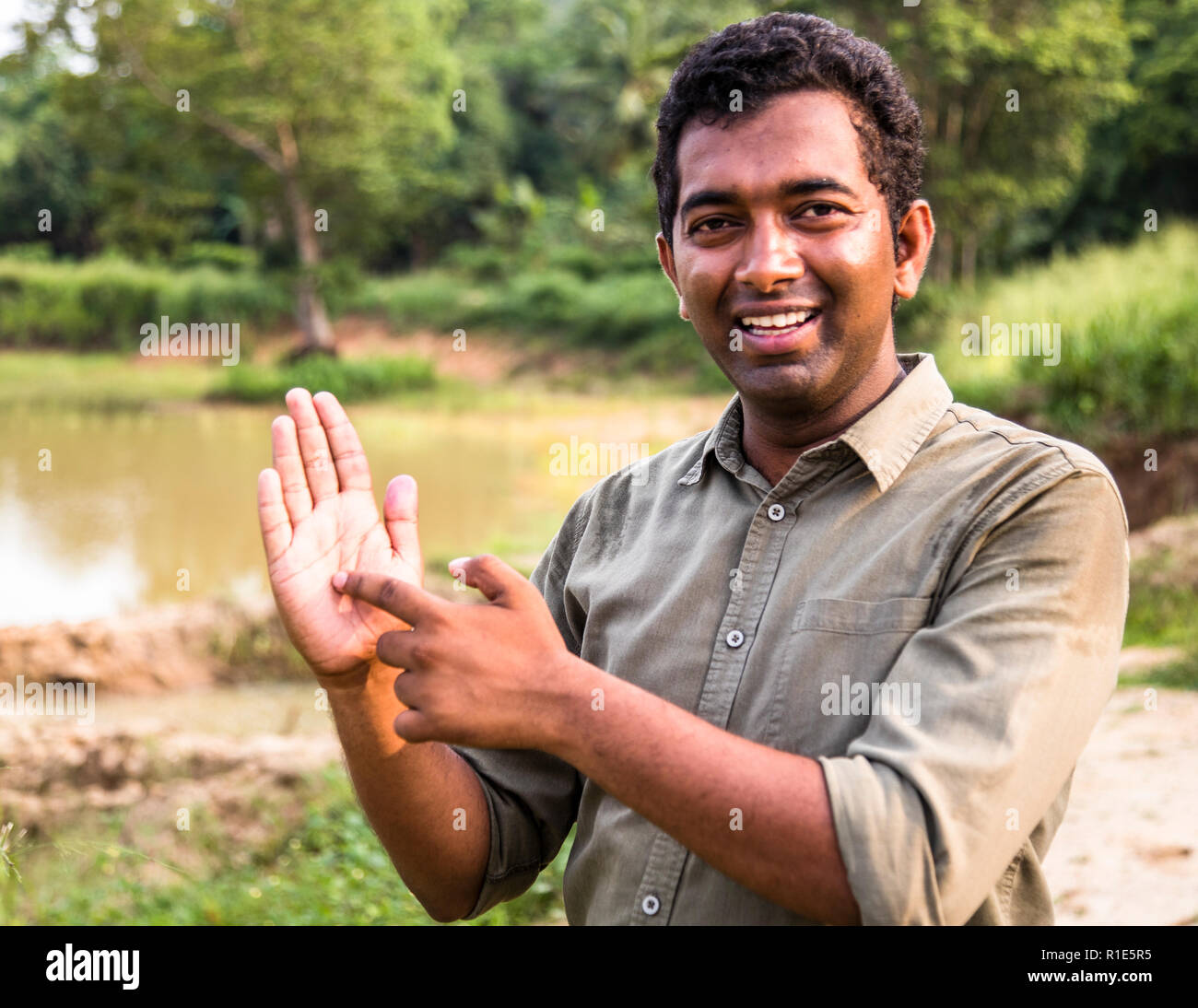 The map of Sri Lanka has the form a drop or a palm. Ishanda shows on the palm of his hand representing Sri Lanka, where we are. As an environmentalist employed by the hotel, he also maintains contact with the village community Stock Photo