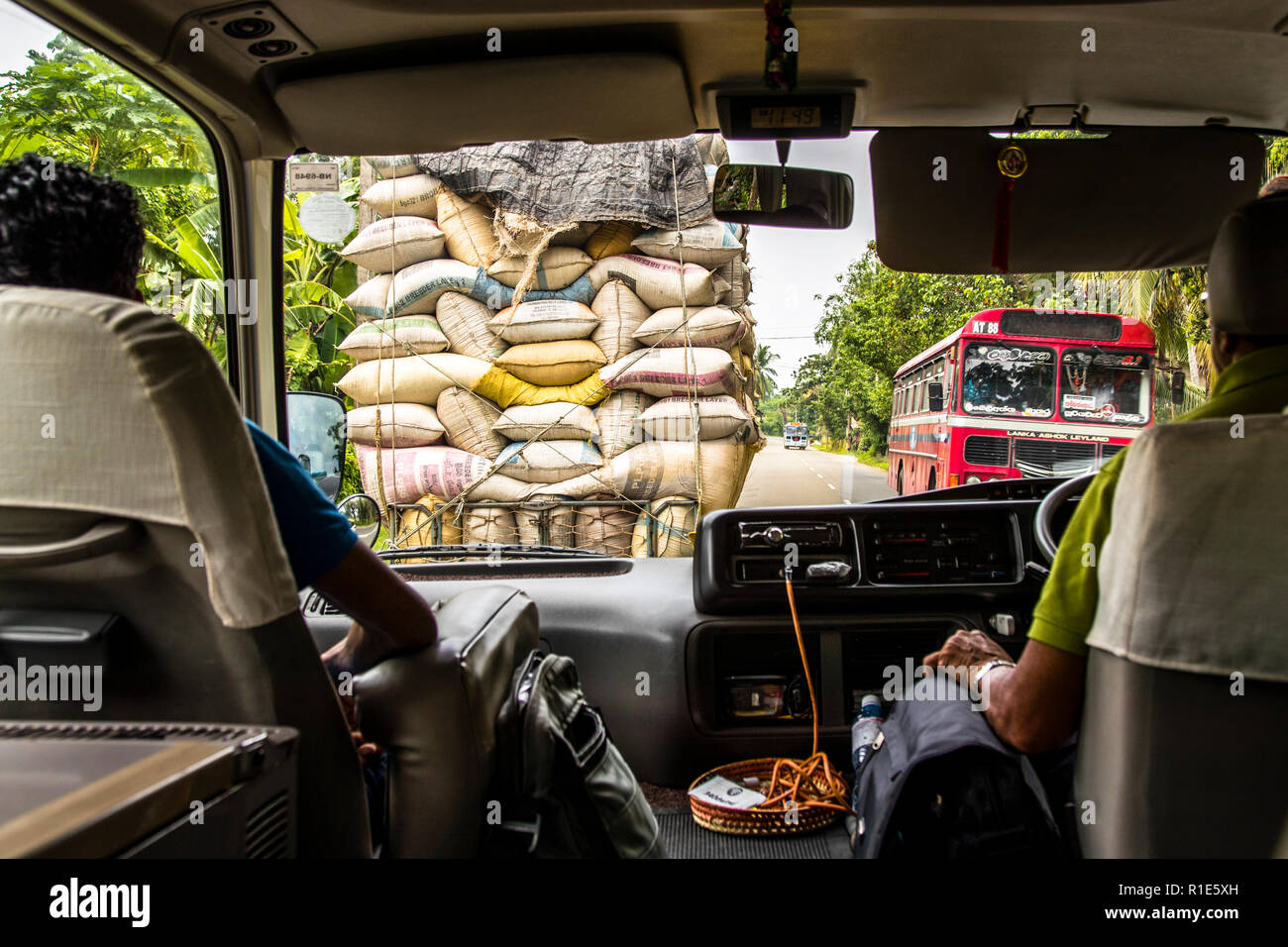 On the way with the bus in the traffic of Sri Lanka. In left-hand traffic in front of us a truck highly loaded with sacks Stock Photo