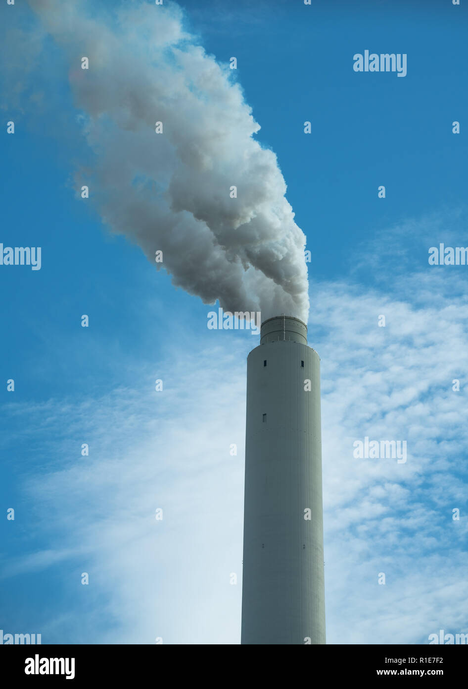 Smoke stack portrait orientation white smoke against blue sky with clouds Stock Photo