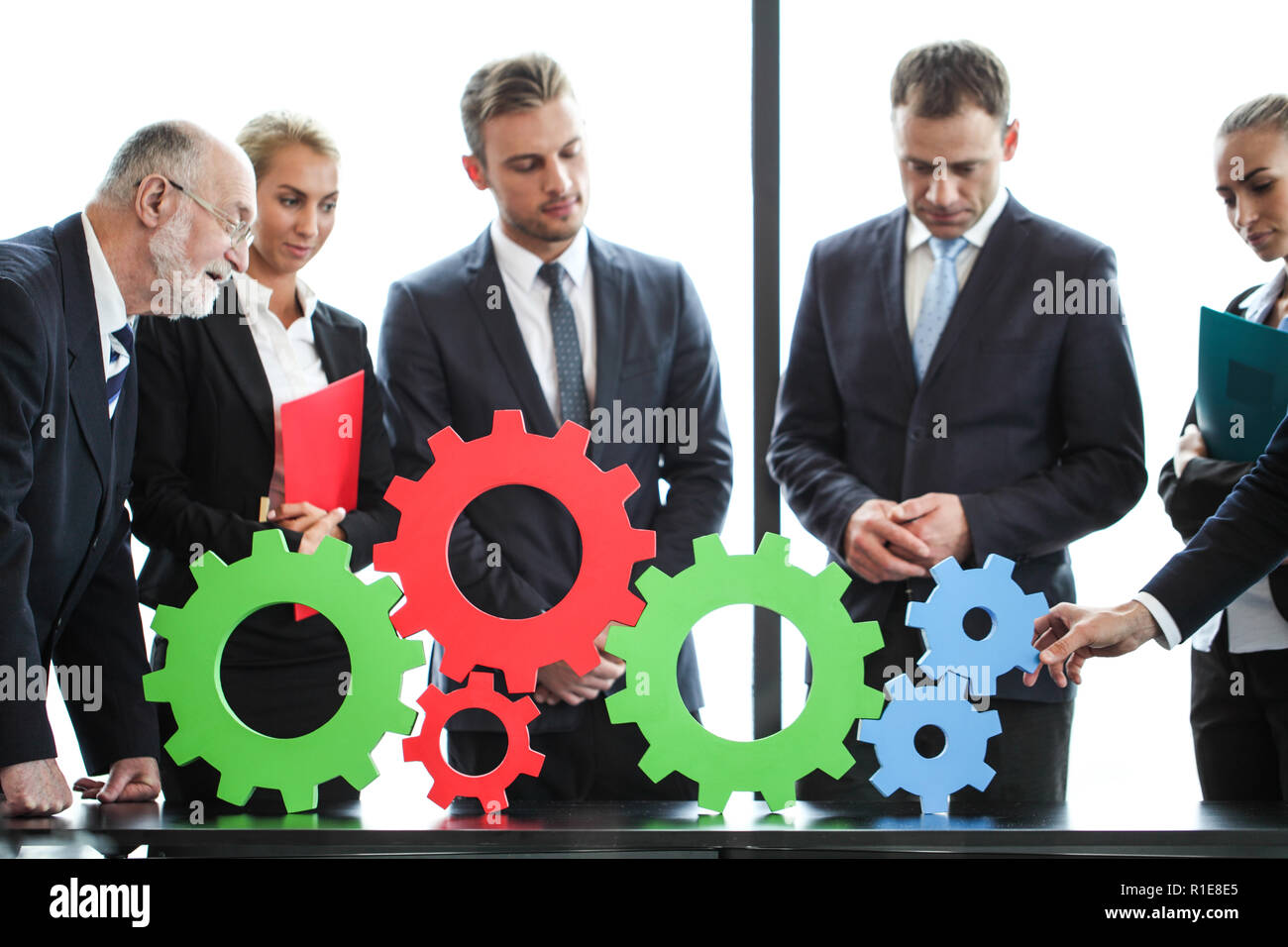 Business people assembling cogwheels, teamwork concept Stock Photo