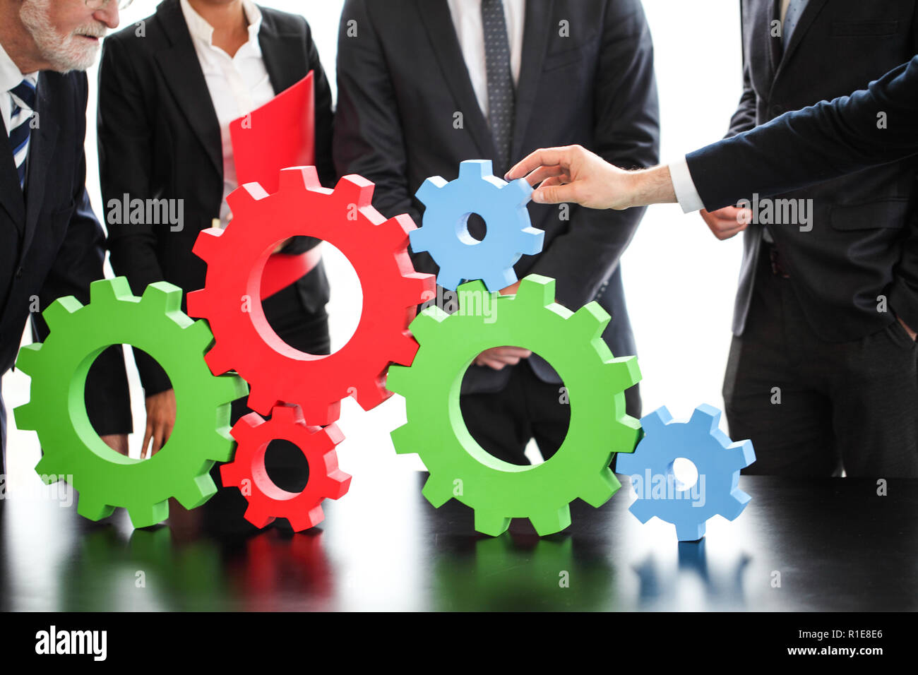 Business people assembling cogwheels, teamwork concept Stock Photo