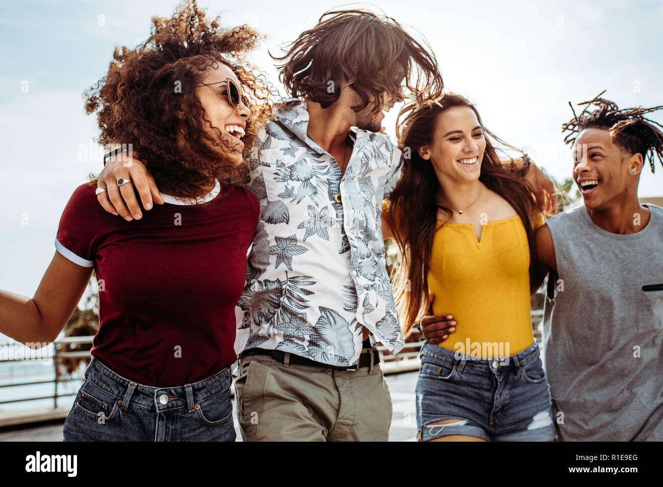 Four young people walking outdoors together. Group of multi-ethnic men and women having fun outdoors. Stock Photo