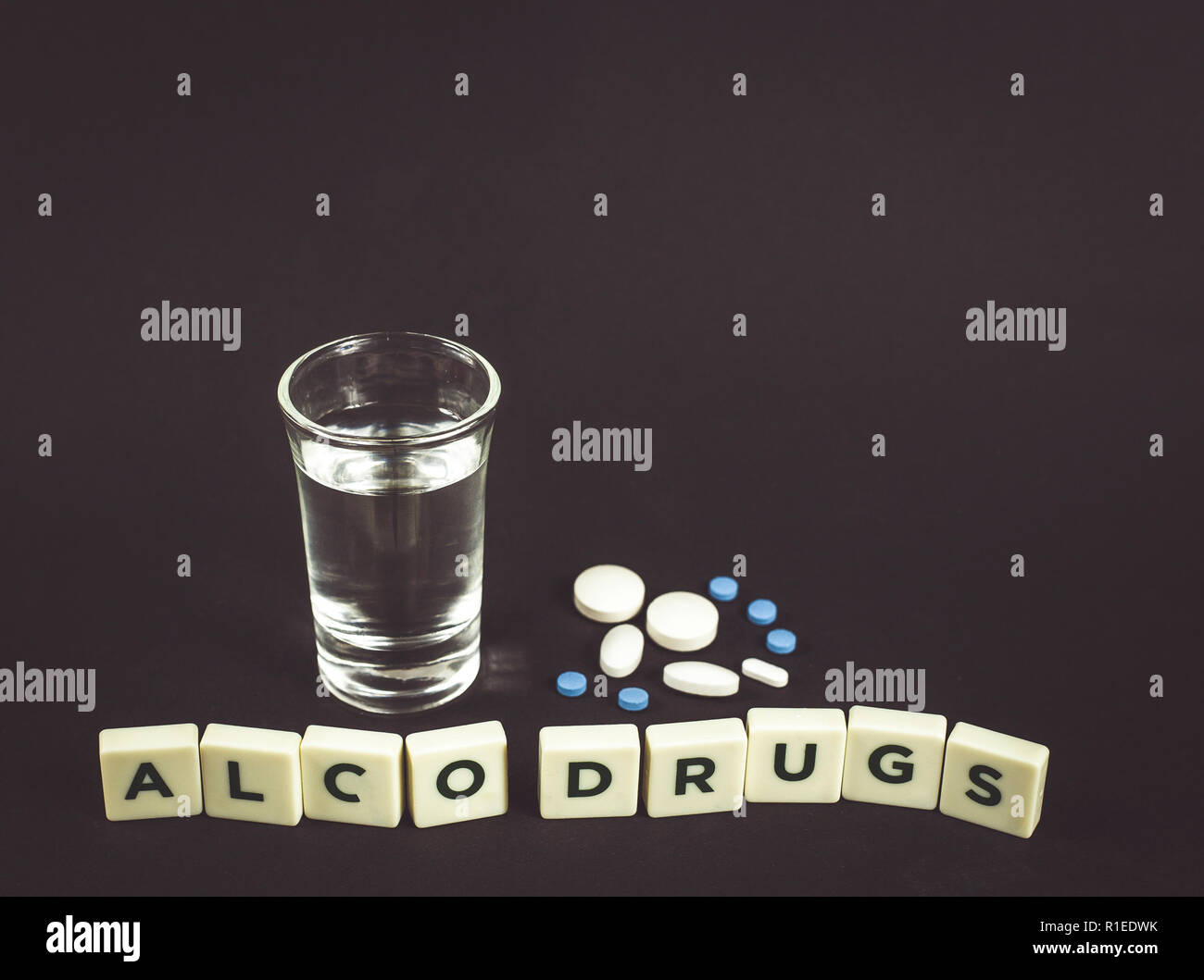 Drinking strong alcohol and taking drugs at the same time could be dangerous concept. Bad for your health, no game concept, dark black background. Stock Photo