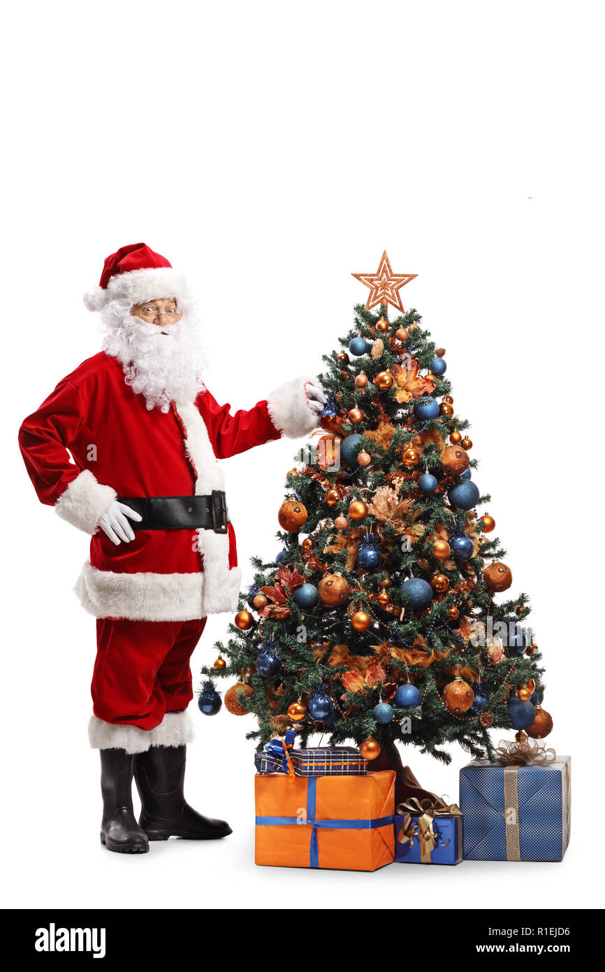 Full length shot of Santa Claus decorating a Christmas tree and looking ...