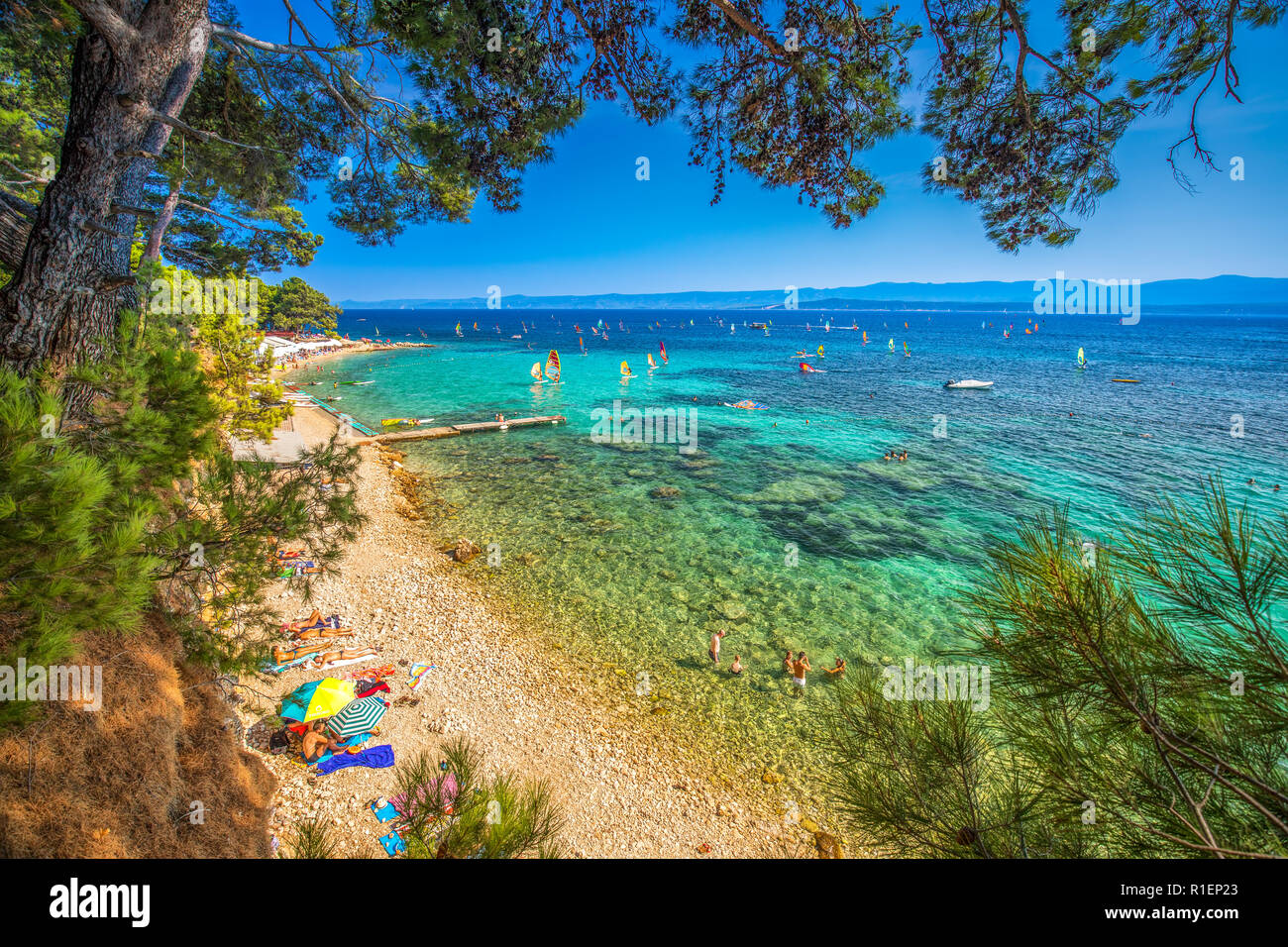 Seaside promenade on Brac island with pine trees and turquoise clear ocean water, Bol, Brac, Croatia. Stock Photo