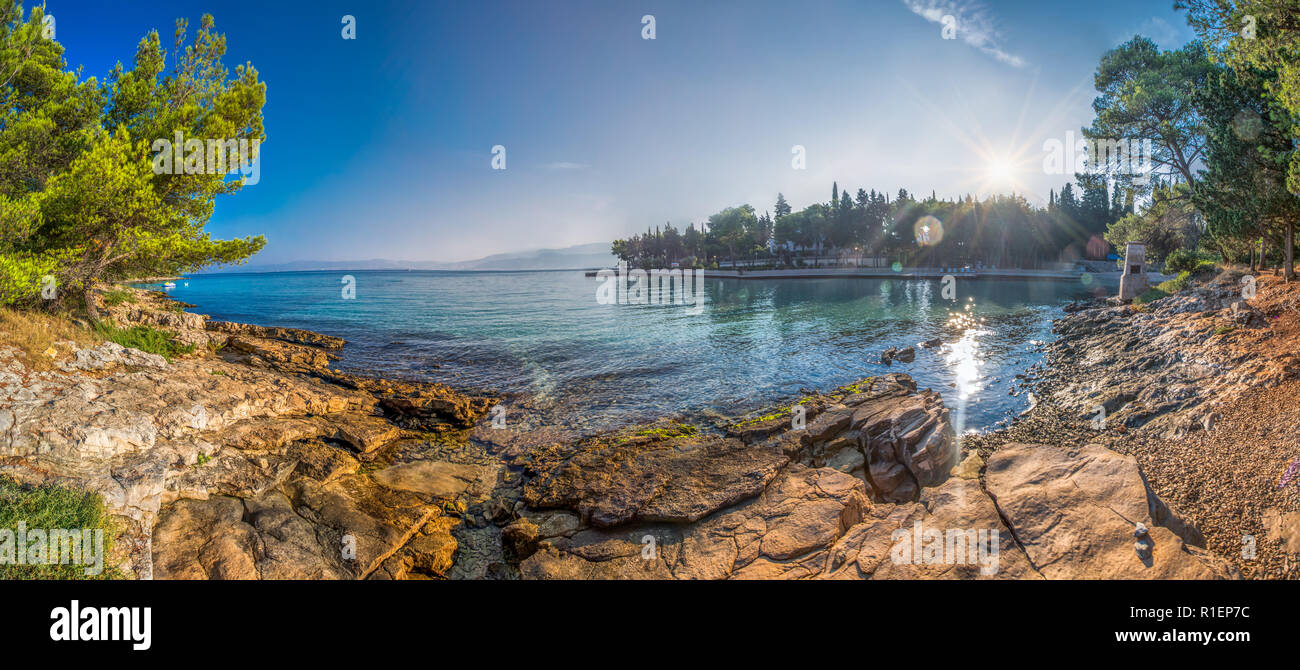 Pebble beach on Brac island with pine trees and turquoise clear ocean water, Supetar, Brac, Croatia Stock Photo