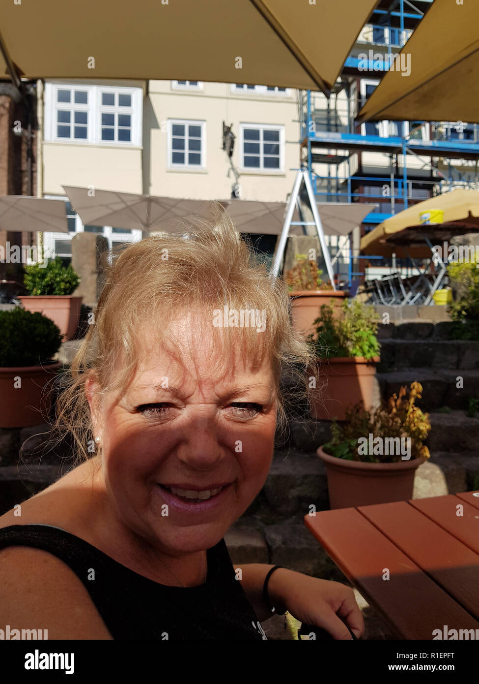 Lueneburg, Lower Saxony, Germany - JULY 28, 2017: Woman sitting in the beer garden of a restaurant in Lüneburg and laughing in the camera Stock Photo