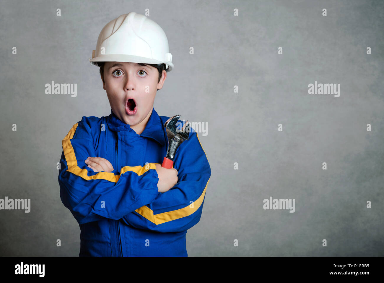 surprised child with a white helmet on gray background Stock Photo