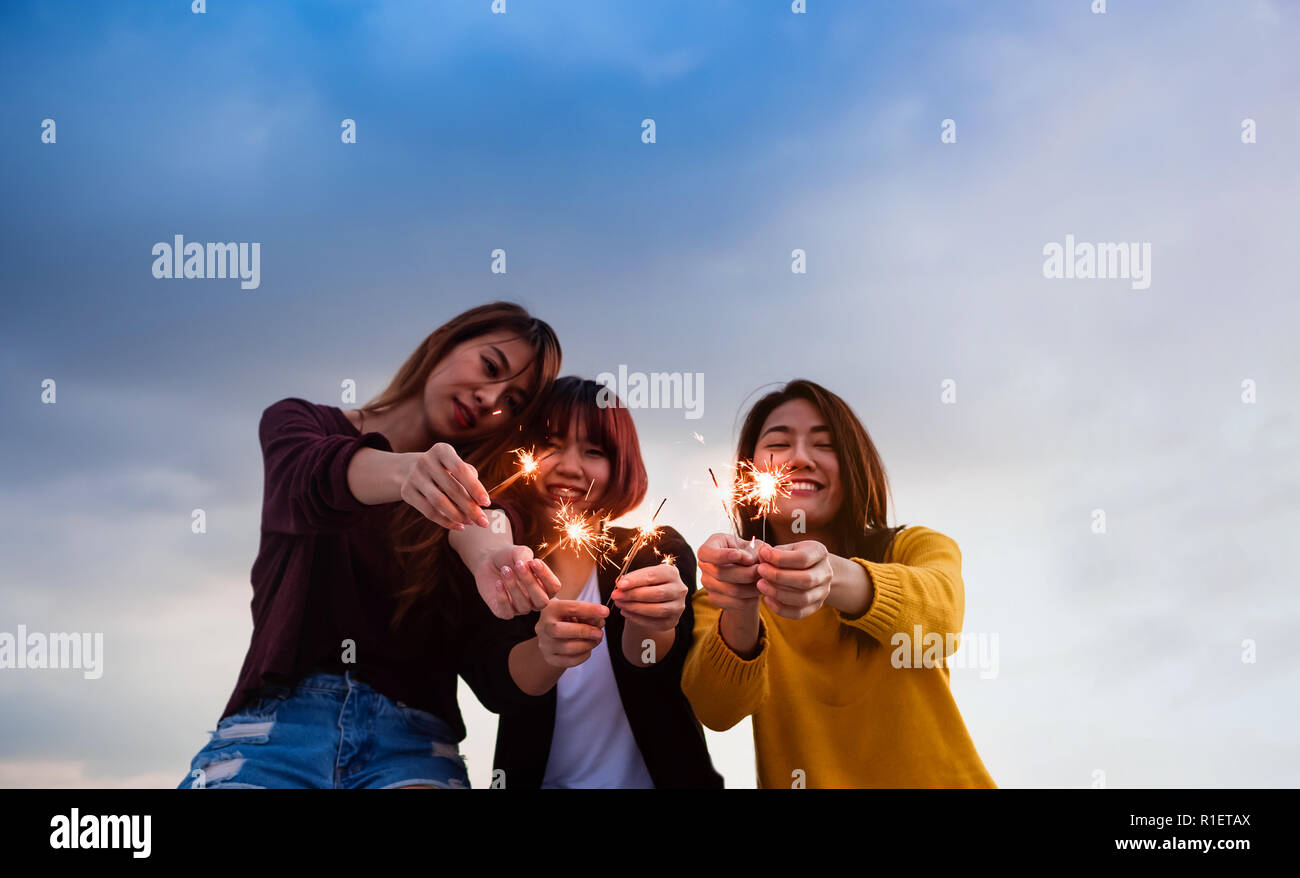 Happy group of asian girl friends enjoy and play sparkler at roof top party at evening sunset,Holiday celebration festive,teeage lifestyle,freedom and Stock Photo