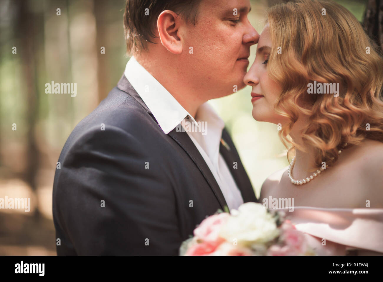 bride and groom kiss on the background of trees and forest Stock Photo ...