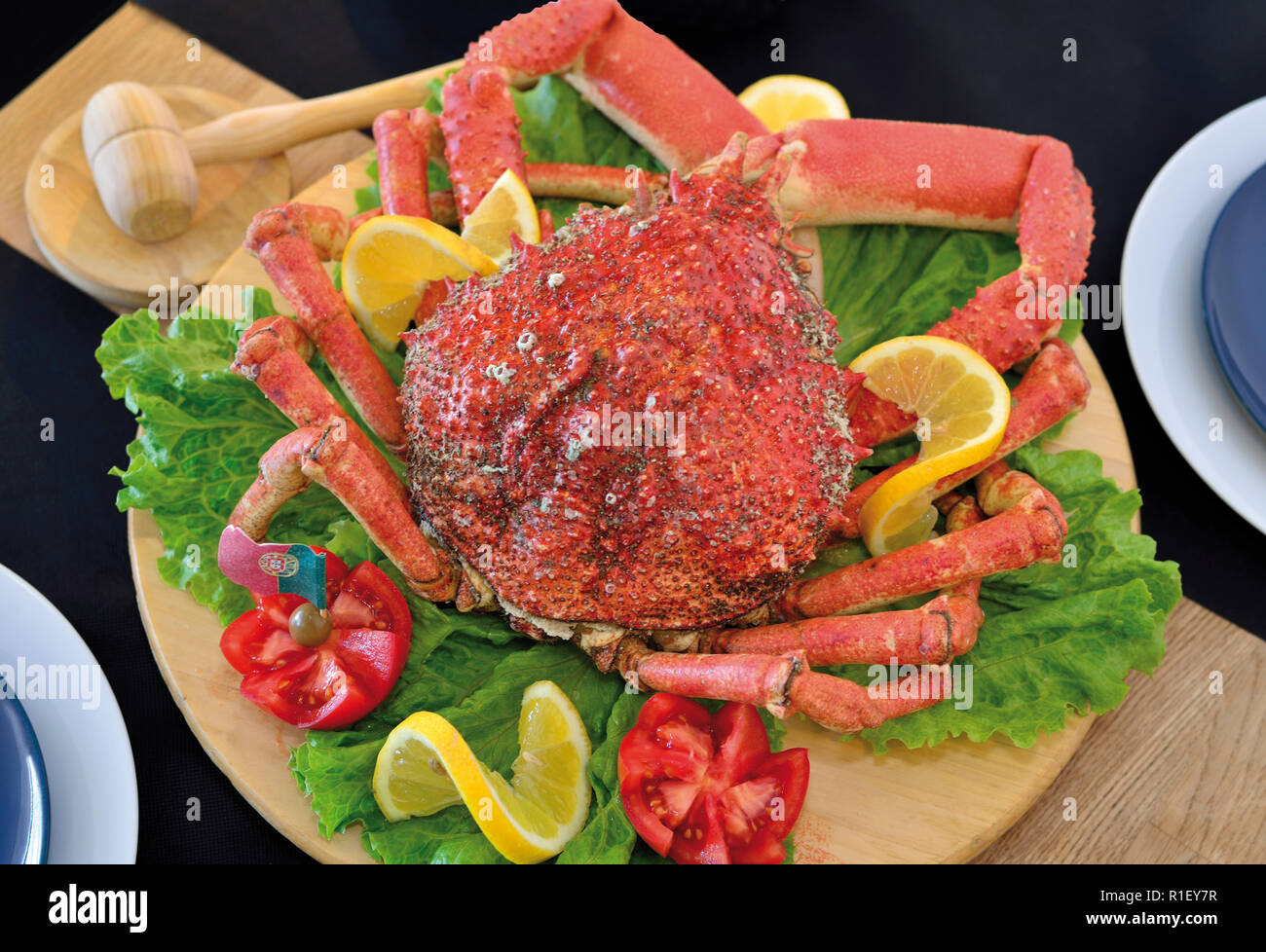 Fresh cooked spider crab on a wooden plate decorated with salad, tomatoes and lemon slices Stock Photo