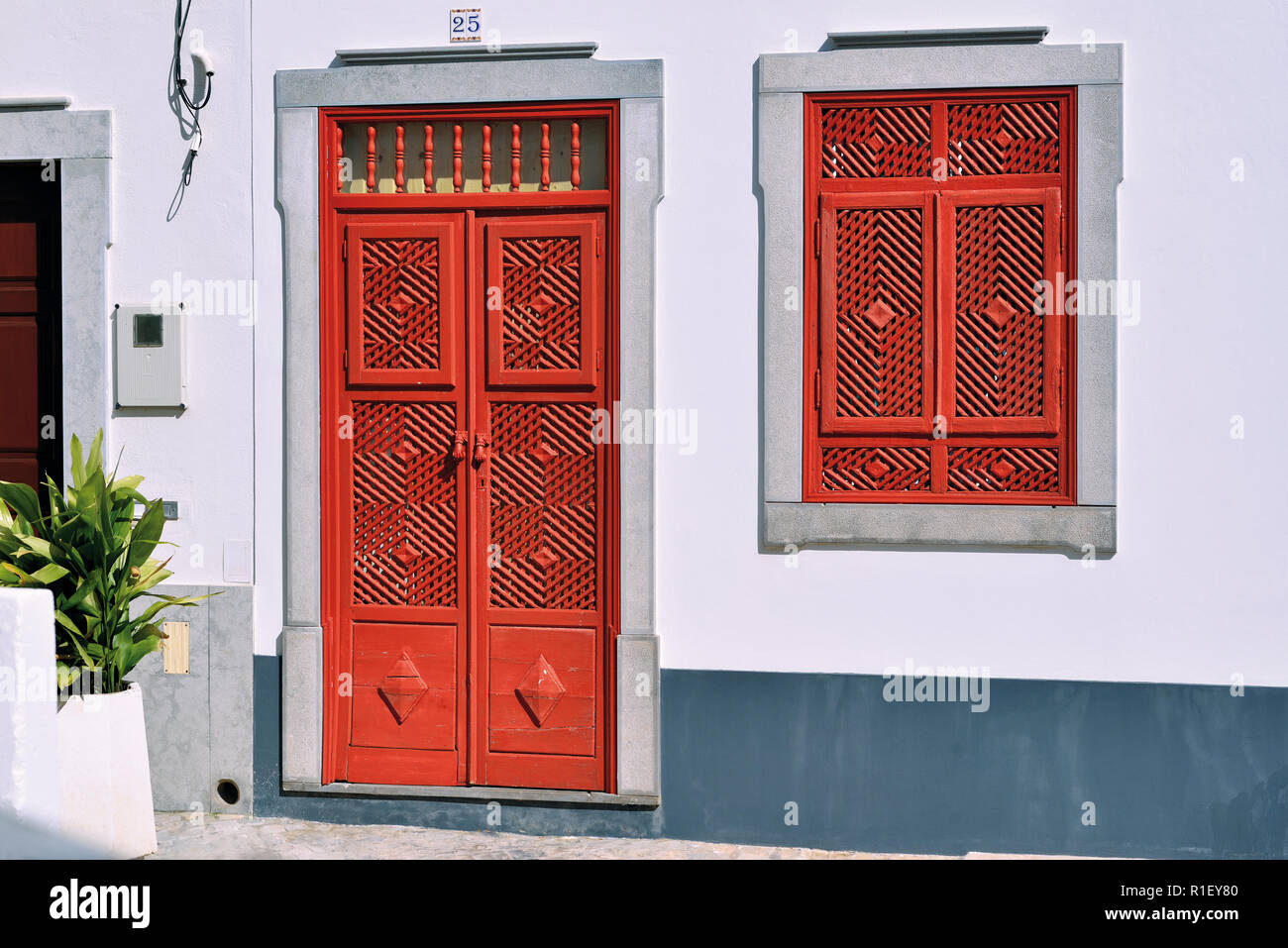 Red door and window in traditional arabian style with various divisions in recently restored small house Stock Photo