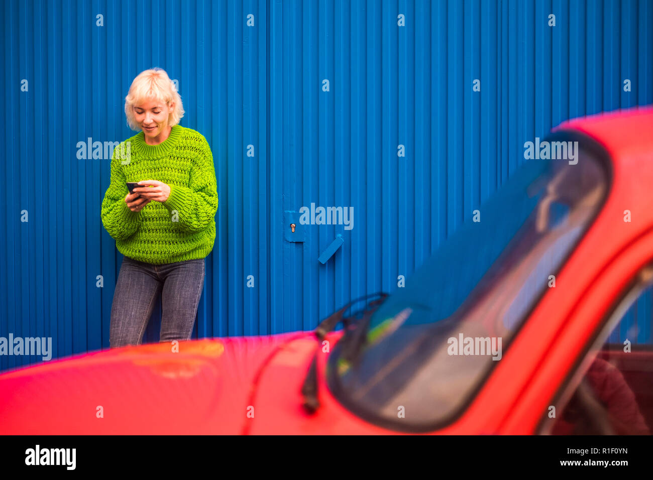 Fashion Coloured Concept Image With Blonde Caucasian Girl Standing Near A Red Vintage Old Car With Blue Steel Wall In Backgorund Urban And Colors Wit Stock Photo Alamy