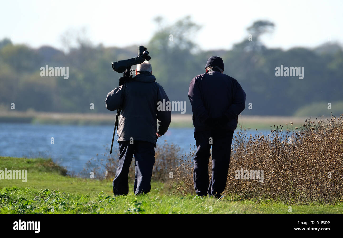 Two birders or twitchers with spotting scope on large fresh water lake. Stock Photo