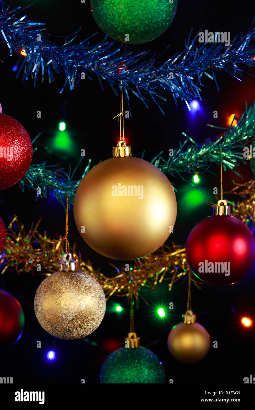 Close up of hanging Christmas decorations and Christmas/fairy lights against a black background. Stock Photo