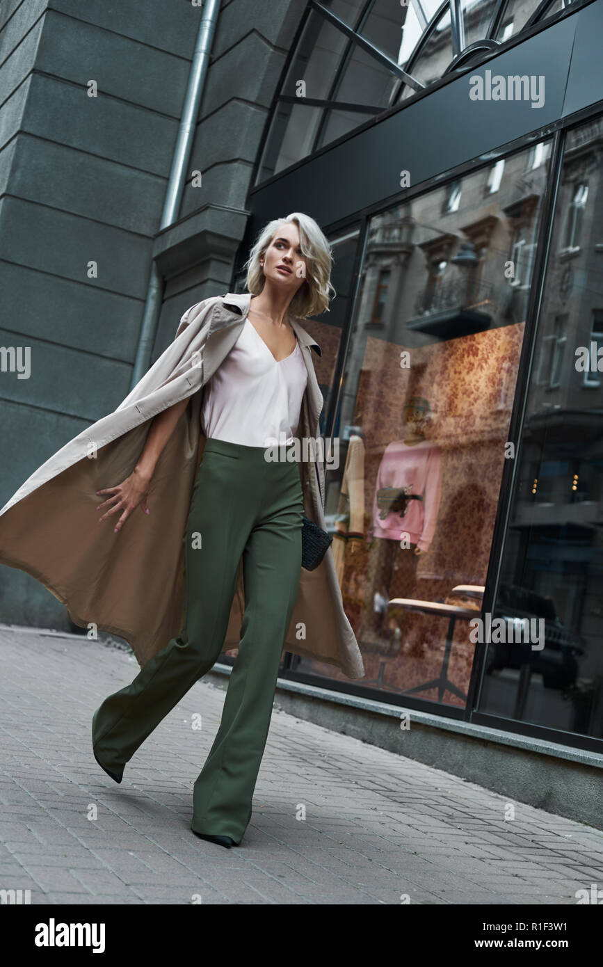 Fashion. Young stylish woman walking on the city street looking aside ...