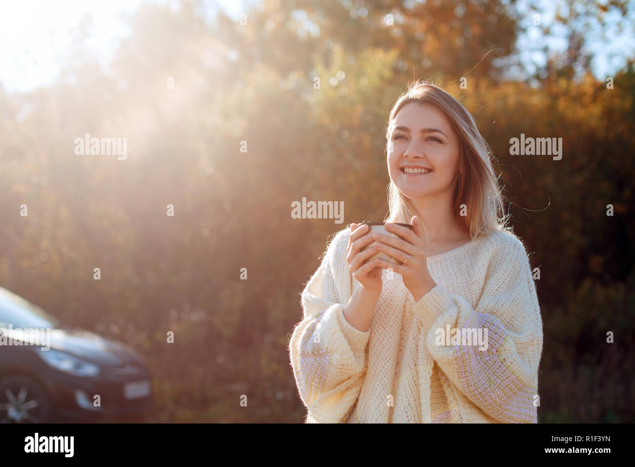 Beautiful admiring woman drinking hot tea from thermos cup Stock Photo