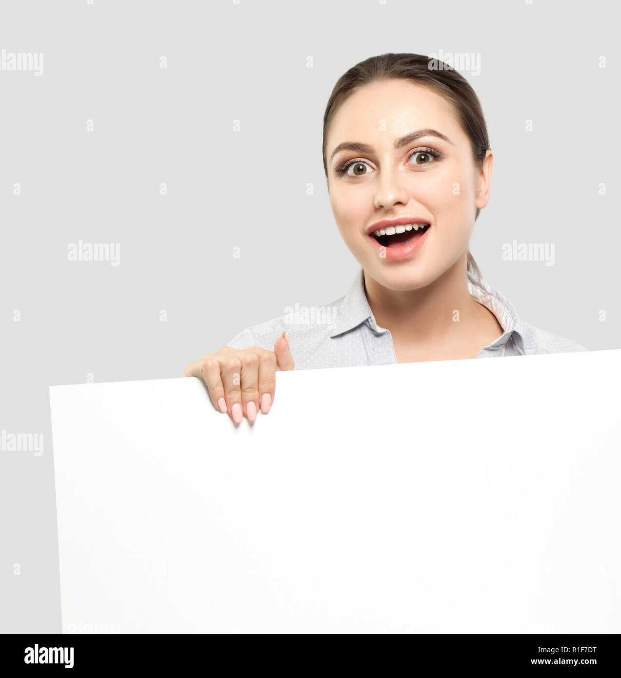Happy surprised businesswoman with white empty board background. Young cheerful woman, business and education concept Stock Photo