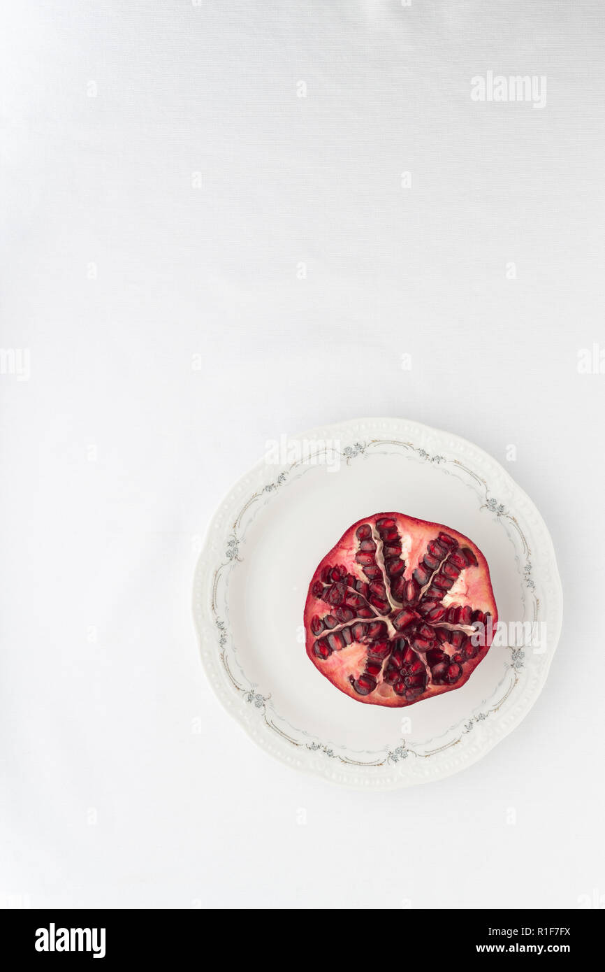 aufgeschnittener Granatapfel von oben auf einen Porzellan Teller Stock Photo