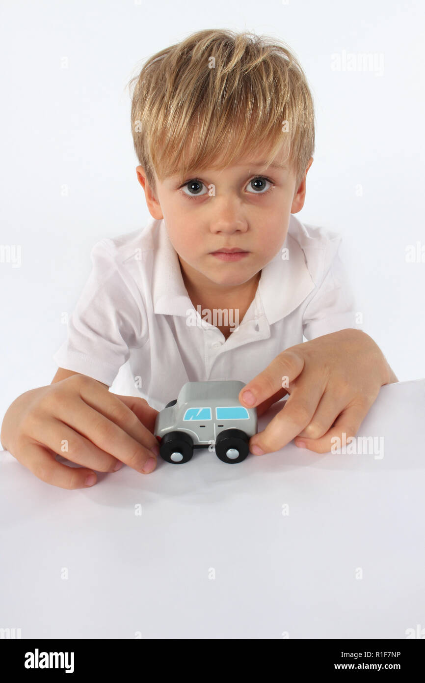 Adorable little boy playing with a small wooden car toy Stock Photo