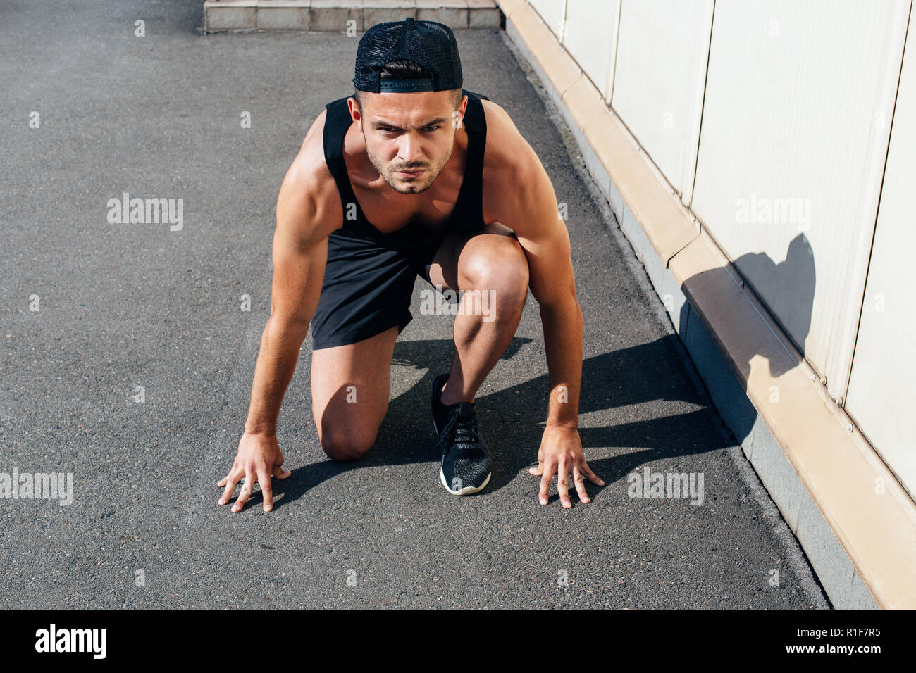 Sprinter Posw Runner in running start pose on the city street. sprinter training ...