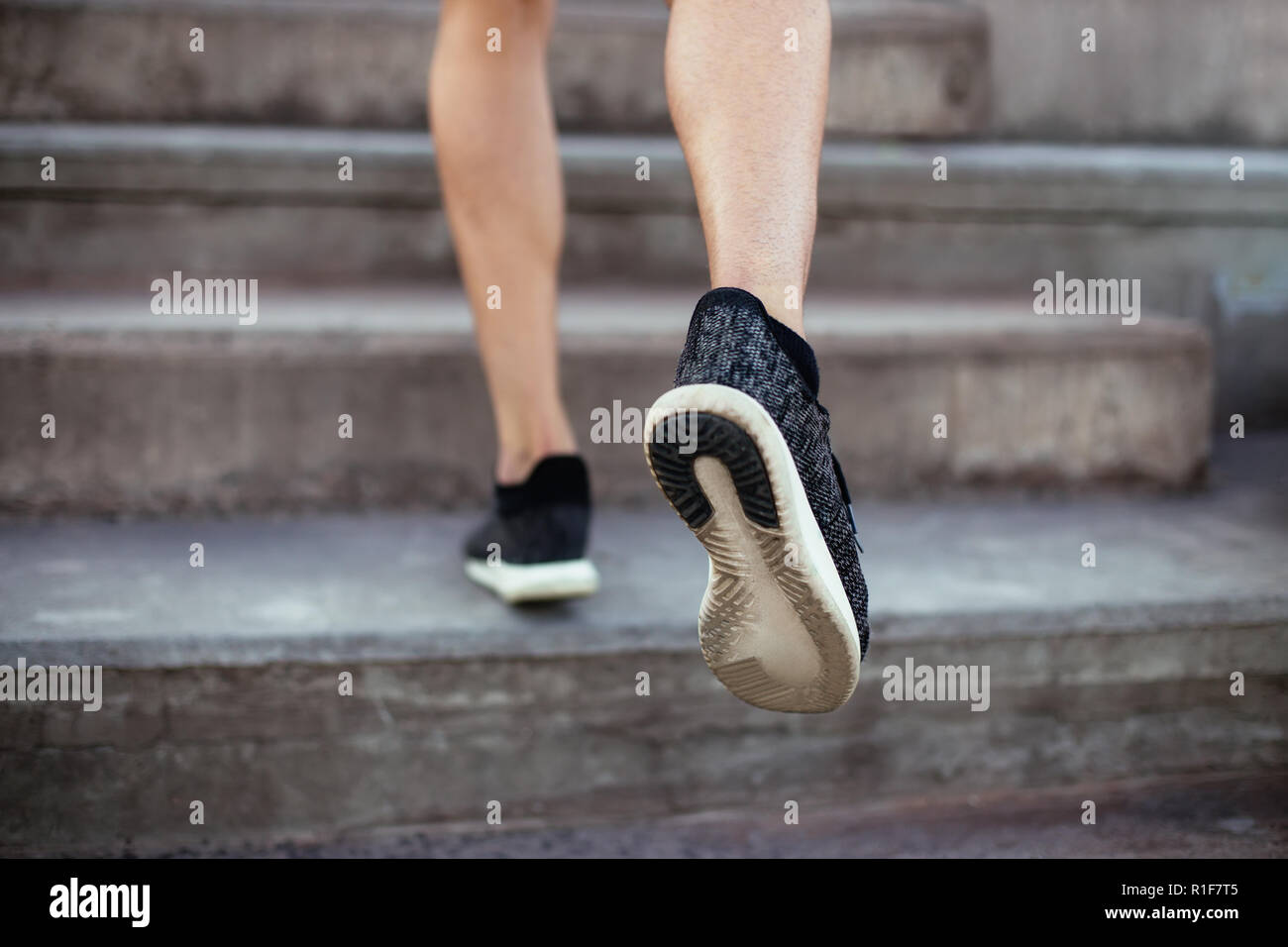 Close up of male feet in sneakers walking up the stairs. Athlete man legs running up Stock Photo