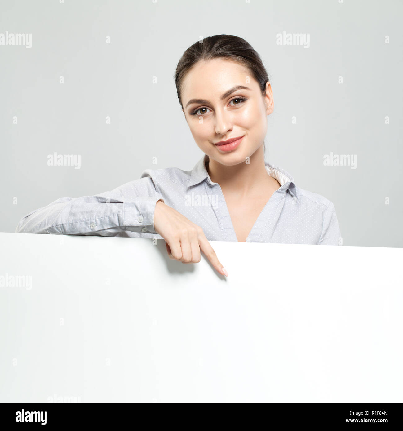 Happy businesswoman pointing and holding white empty signboard background. Young woman smiling, business and education concept Stock Photo