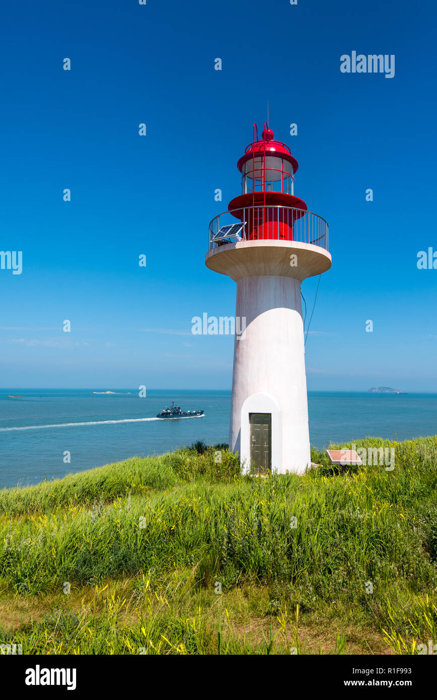 CHANGDAO ISLANDS, SHANDONG, CHINA - 19JUL2018: Lighthouse at Xibeizui on the north west of Beichangshandao Island near Longtoujiao with  Chinese ship  Stock Photo
