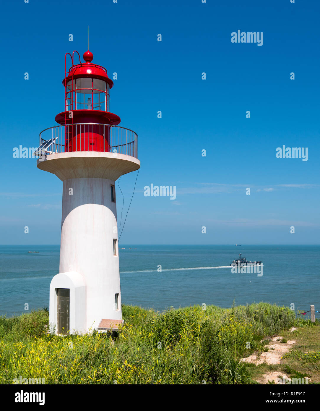 CHANGDAO ISLANDS, SHANDONG, CHINA - 19JUL2018: Lighthouse at Xibeizui on the north west of Beichangshandao Island near Longtoujiao with  Chinese ship  Stock Photo