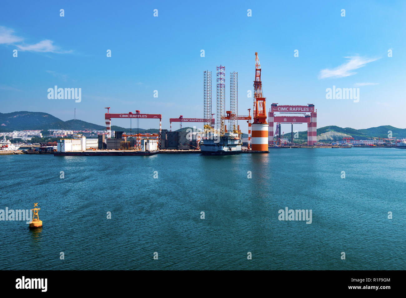 YANTAI, SHANDONG, CHINA - 21JUL2018: The CIMC Raffles Shipyard. To the right is Taisun, the largest gantry crane in the world with a lifting capacity  Stock Photo