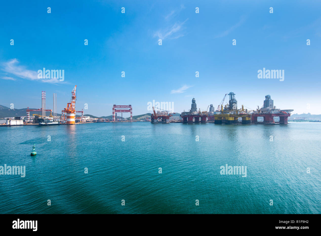 YANTAI, SHANDONG, CHINA - 21JUL2018: The CIMC Raffles Shipyard. To the right are several semisubmersible rigs owned by CIMC. Stock Photo