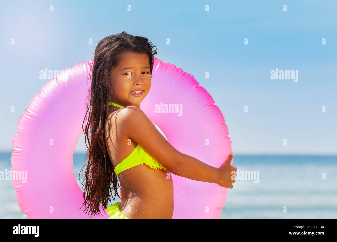 Little Asian girl with swimming ring on the beach Stock Photo - Alamy