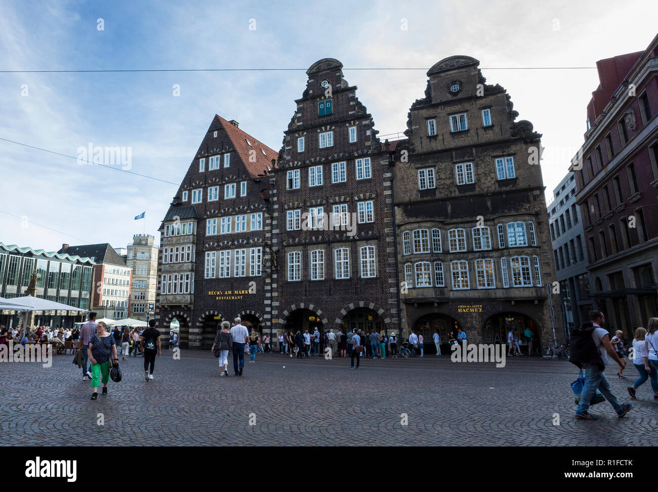 Marktplatz, Bremen. Deutschland Germany.  A scene looking across the market square towards neighbouring business premises whose architecture reflects German traditional styles.  It's a sunny day so there are many tourist holiday makers out exploring and enjoying the sunshine. Stock Photo