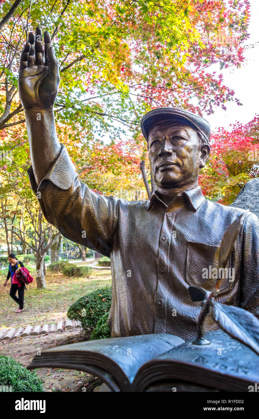 Bronze sculpture of a man waving whilst sat cross legged and reading a book on Nami Island, South Korea Stock Photo