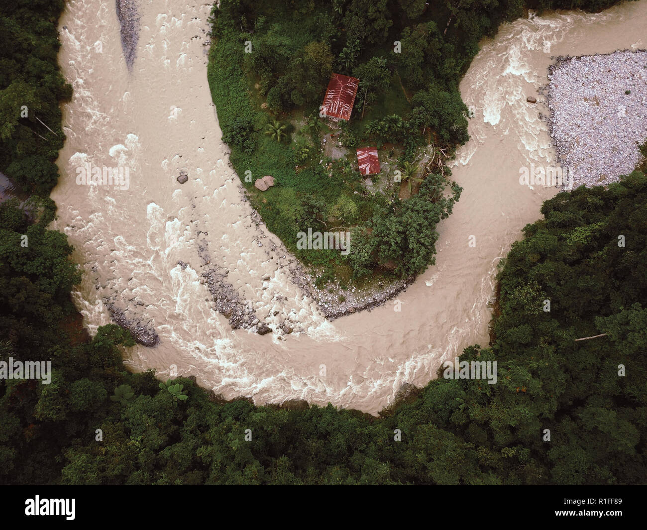 Rainforest River in Indonesia threatening to flood Huts. Drone Shot. Stock Photo