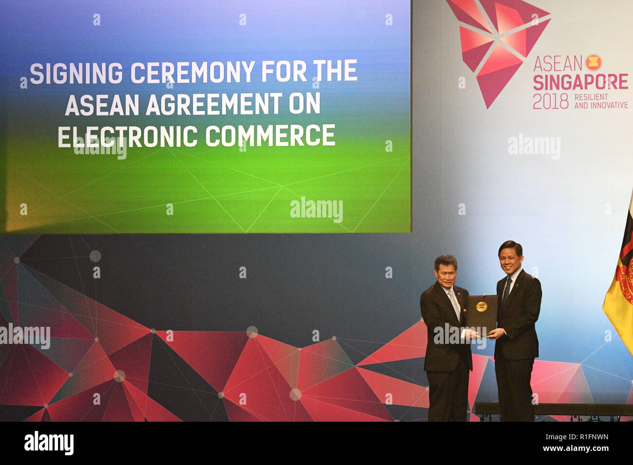 Singapore, Singapore. 12th Nov, 2018. Singaporean Minister for Trade and Industry Chan Chun Sing (R) hands over the signed document to ASEAN Secretary General Lim Jock Hoi during the signing ceremony of ASEAN's agreement on e-commerce, in Singapore, on Nov. 12, 2018. Trade ministers of the Association of Southeast Asian Nations (ASEAN) member states signed an agreement on e-commerce on Monday, encouraging paperless trading between businesses and governments of the bloc to generate rapid and efficient transactions. Credit: Then Chih Wey/Xinhua/Alamy Live News Stock Photo