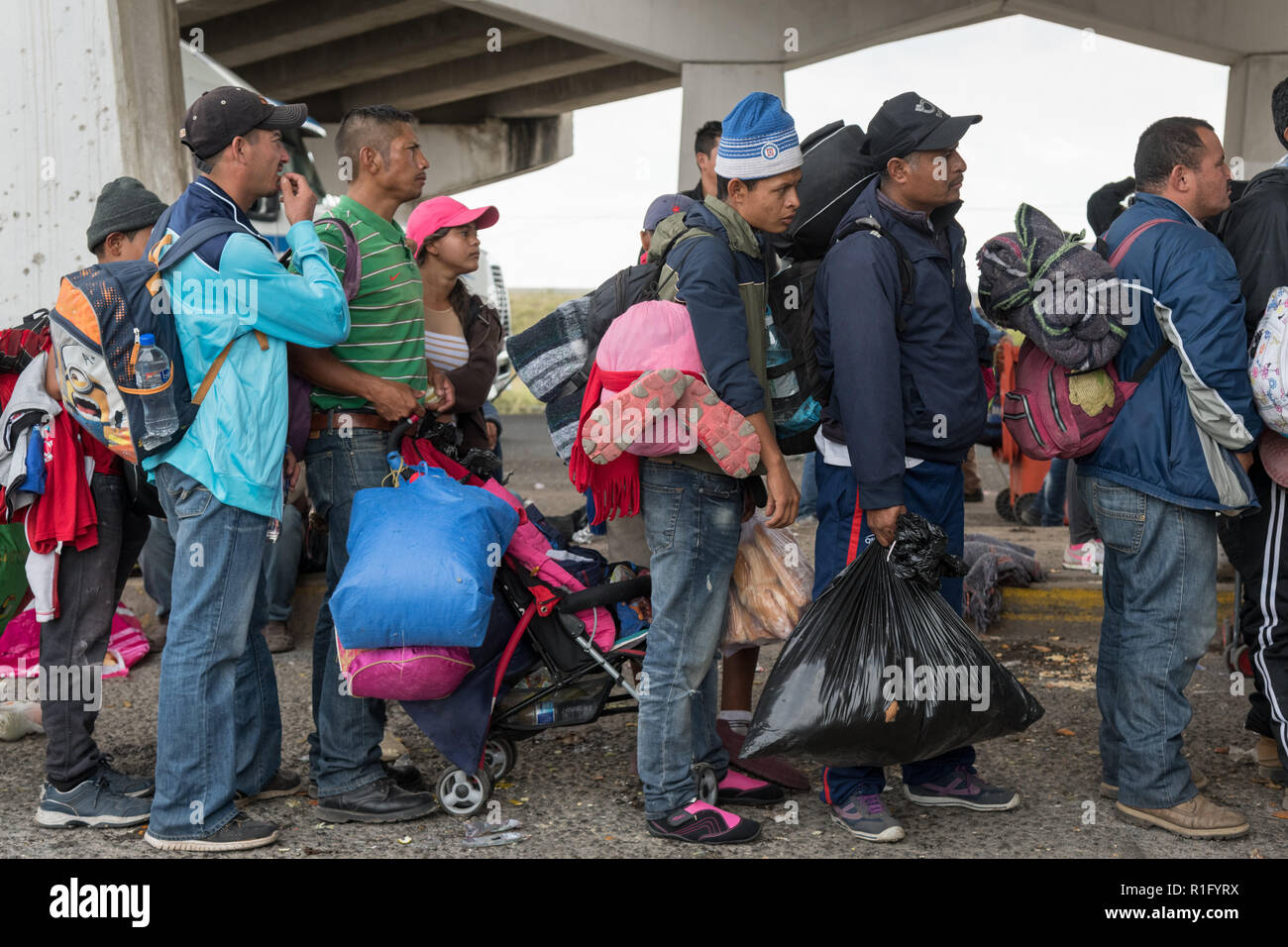 Irapuato, Guanajuato, Mexico. 12th Nov 2018. Honduran refugees with the Central American migrant caravan wait in line for a ride under a highway overpass to continue the journey northwest toward the U.S. border November 12, 2018 in Irapuato, Guanajuato, Mexico. The caravan has been on the road for a month is half way along their journey to Tijuana. Credit: Planetpix/Alamy Live News Stock Photo