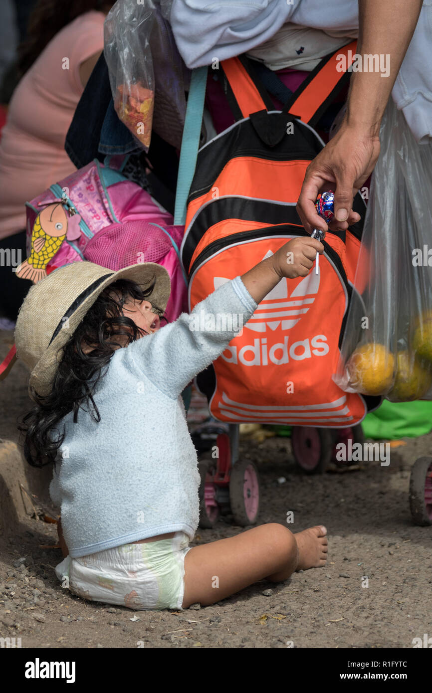 Irapuato, Guanajuato, Mexico. 12th Nov 2018. A young Honduran refugee with the Central American migrant caravan is handed a candy by a volunteer as her family waits to continue the journey northwest toward the U.S. border November 12, 2018 in Irapuato, Guanajuato, Mexico. The caravan has been on the road for a month is half way along their journey to Tijuana. Credit: Planetpix/Alamy Live News Stock Photo