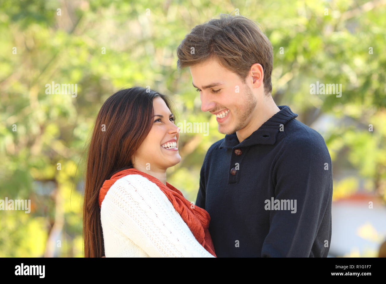 Happy couple looking each other falling in love outdoors in a park Stock Photo