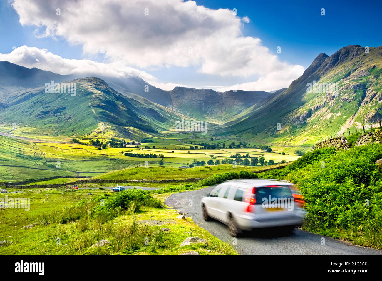 Car in motion on a countryside road above Great Langdale valley, with a stunning view over the Lake District hills, UK Stock Photo