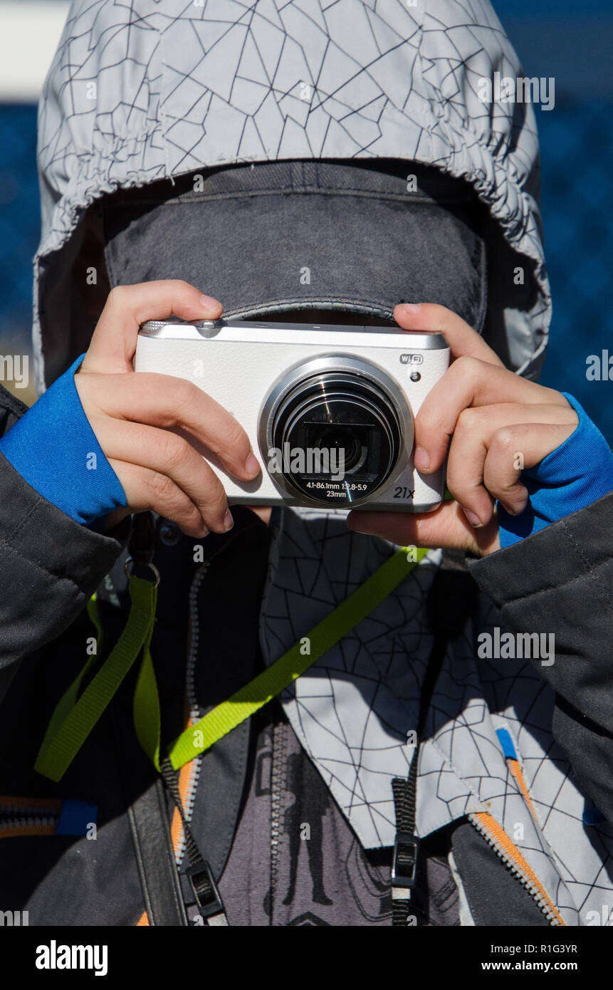 Closeup frontal of young boy holding camera taking photograph. Stock Photo