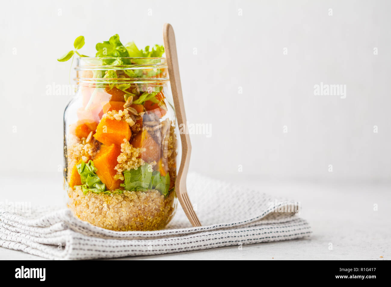 Pumpkin, quinoa salad in a jar on white background. Take away food, picnic food. Stock Photo