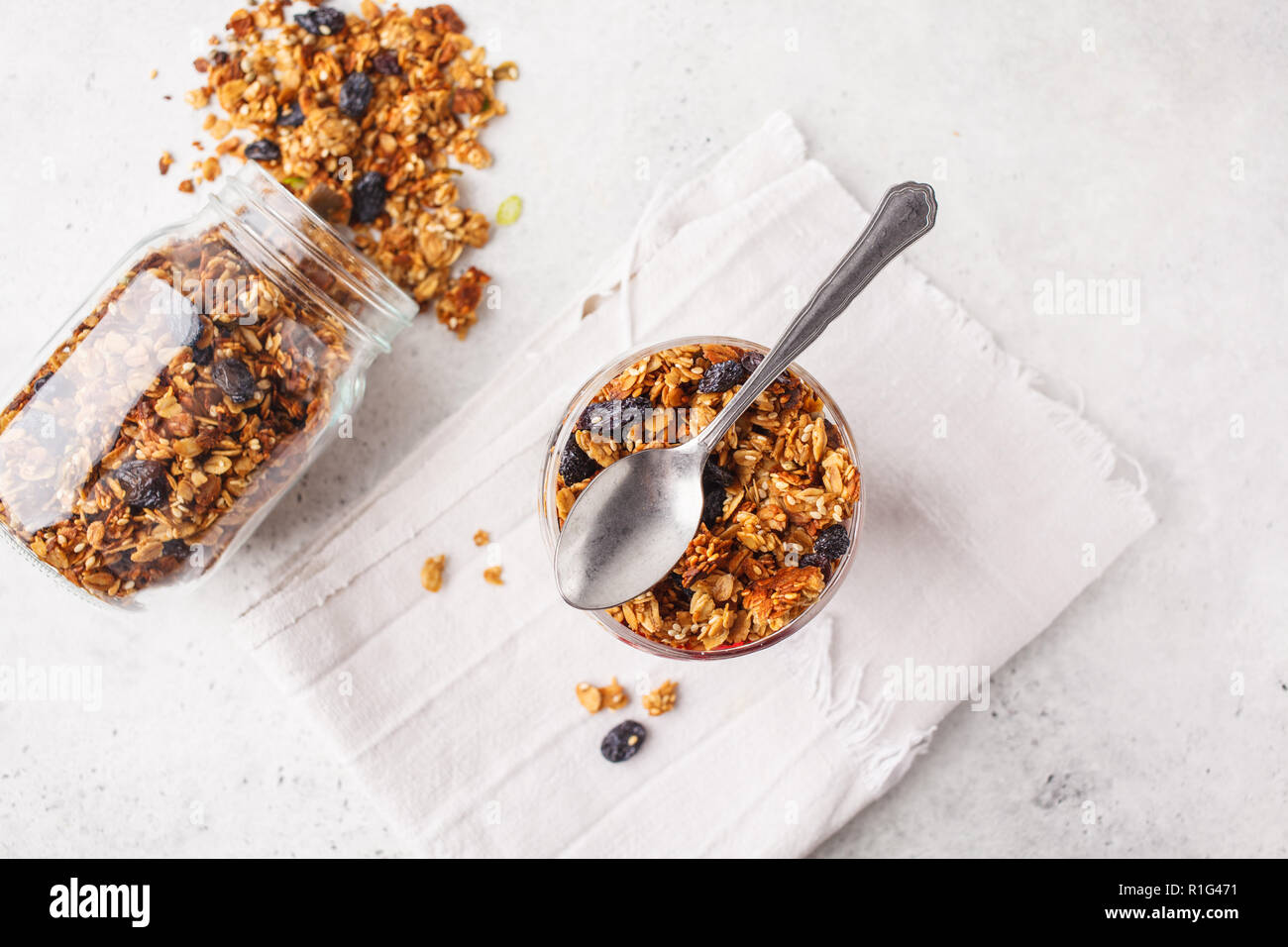 Baked granola with raisins in gray bowl, white backgroundl. Vegan