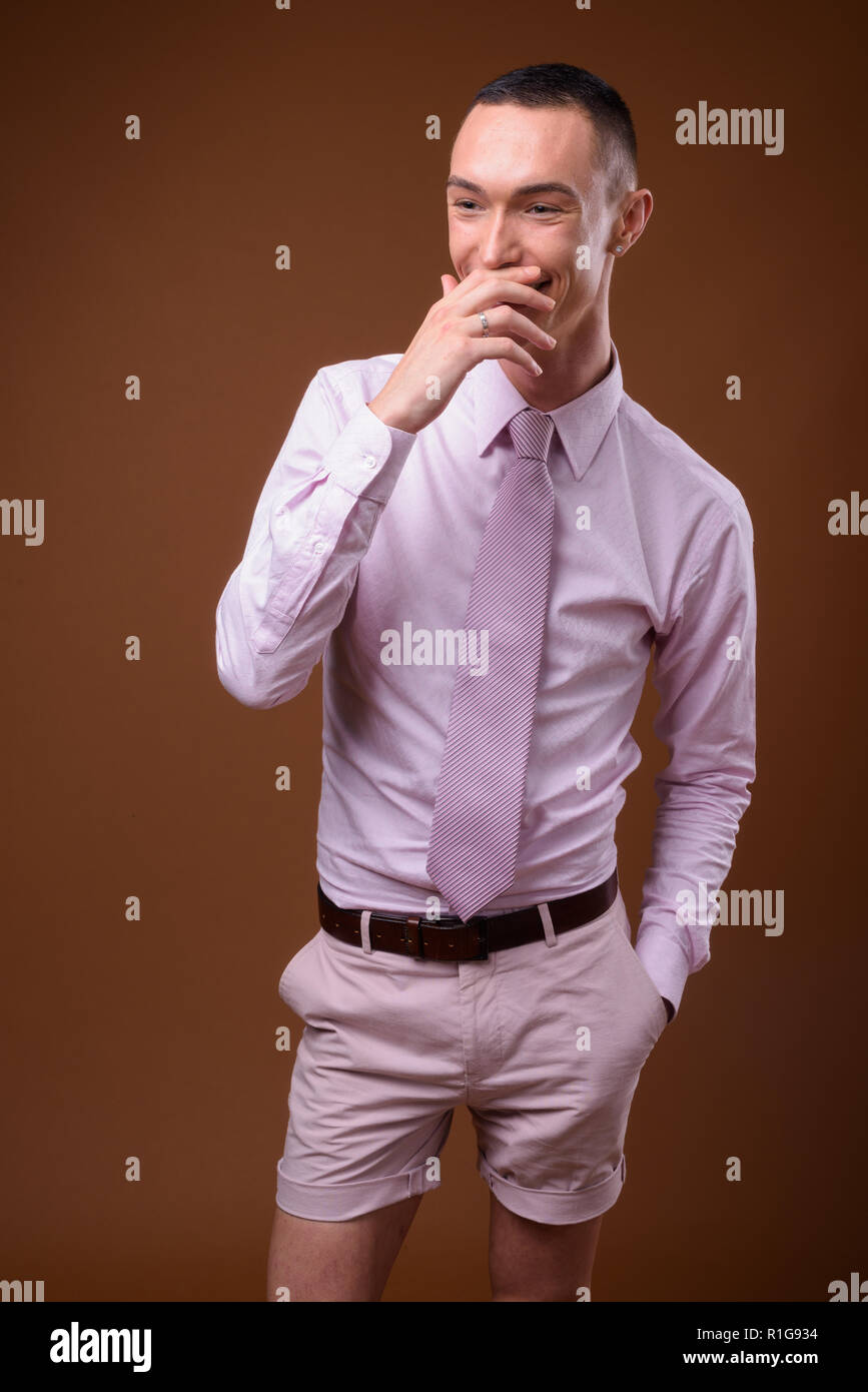 Young handsome androgynous businessman against brown background Stock Photo