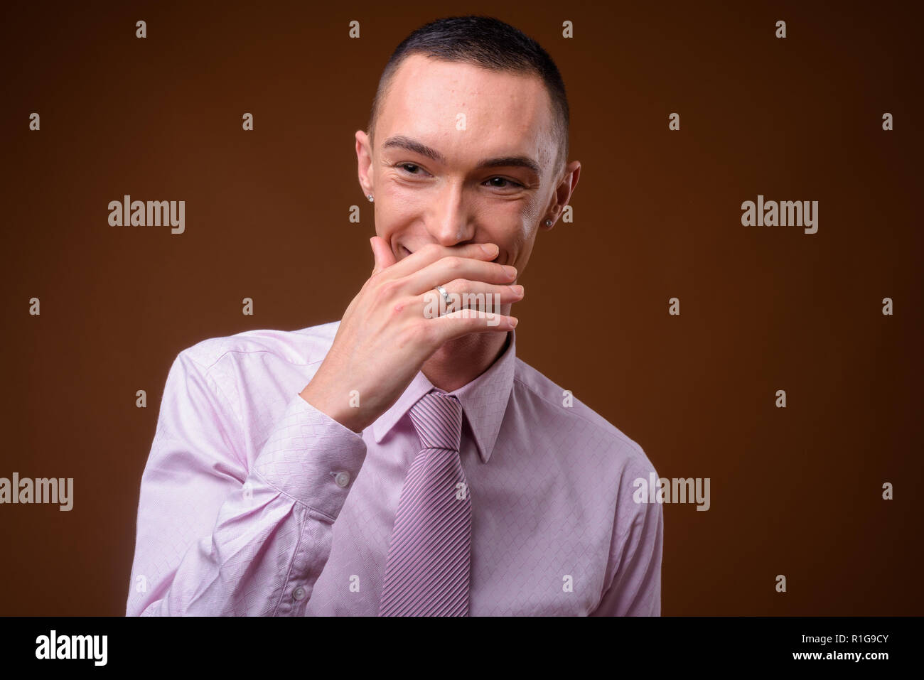 Young handsome androgynous businessman against brown background Stock Photo