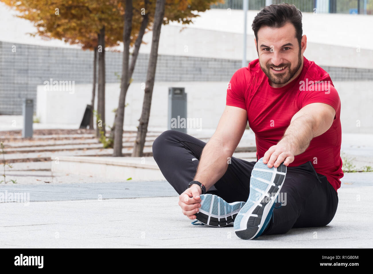 Man with sportive clothes doing leg stretches exercises Stock Photo